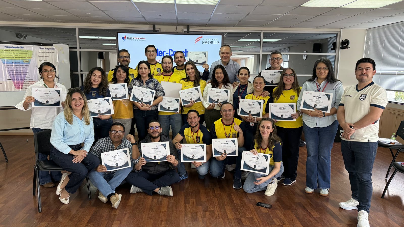 Participantes de Corporación Favorita sosteniendo sus certificados de Líder-Coach.