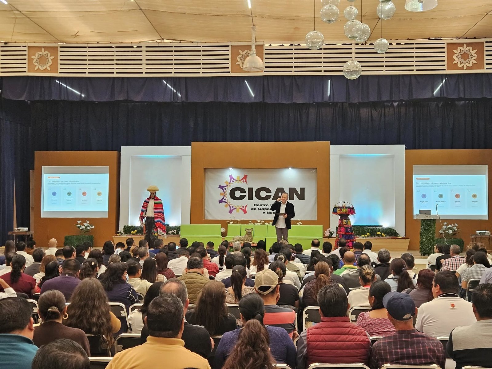 David Murphy en el escenario del CICAN, frente a un auditorio lleno de docentes sentados de espaldas a la cámara.