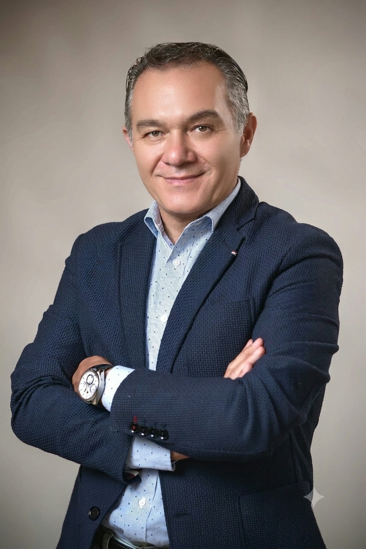 Retrato de estudio de David Murphy Ruiz, saco azul marino, de brazos cruzados.