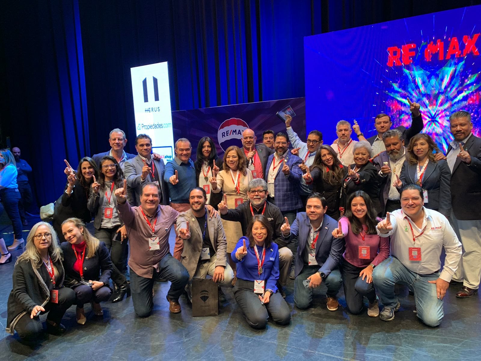 Brokers y gerentes de la red RE/MAX reunidos en el escenario de una convención.